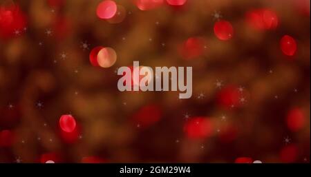 Schneeflocken fallen gegen rot leuchtende Lichtpunkte Stockfoto