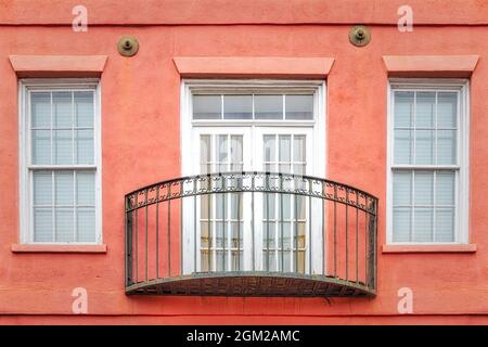 Charleston Charm SC - Französische Türen, Fenster mit Eisengeländer schmücken die Fassade dieses pastellfarbenen Hauses in Rainbow Row in Charleston, South Carol Stockfoto