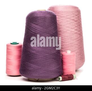 Gruppe von Konen und Spulen aus violettem und violettem Kunststoff oder Baumwollfäden auf weißem Hintergrund, die für das Weben in der Textilherstellung verwendet werden Stockfoto
