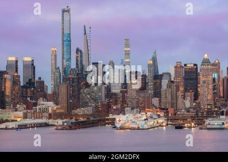 NYC Skyline USNS - Blick auf den USNS Comfort, der am Pier 90 an der Skyline von Midtown Manhattan in New York City, NY, während der Blauen Stunde des Zwielns angedockt ist Stockfoto