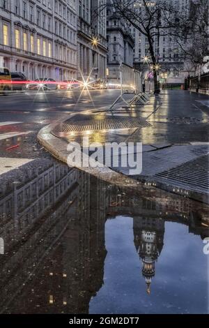 NYC Manhattan Municipal Building - Blick auf die obere Fassade des Manhattan, New York City Municipal Building in einer Wasserpfütze reflektiert. Das eklektische Stockfoto