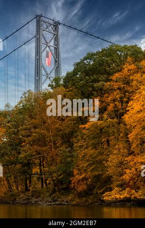 Bear Mountain Bridge Autumn - Blick nach Süden auf die Bear Mountain Bridge, und die Amrican Flagge drapiert über einem der Rungen im Herbst mit seinen m Stockfoto