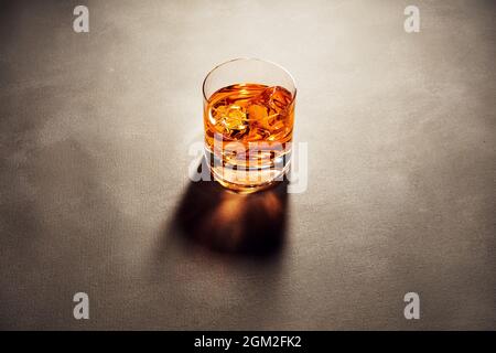 Ein Glas eleganter Whiskys mit Eiswürfeln an der Theke mit dunkler launischer Atmosphäre. Drink Art Konzept. Stockfoto