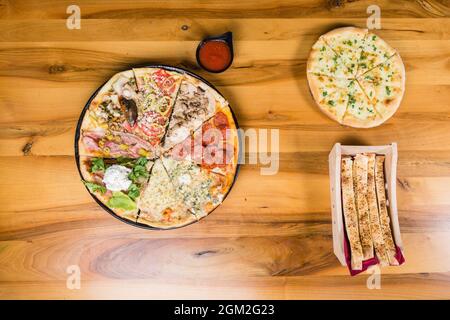 Verschiedene Pizzaarten kombiniert in einem mit Tomatensauce, Brotstäbchen und Pizzabrot Stockfoto