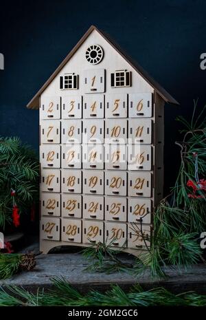 Adventskalender aus Holz für das Warten auf Neujahr oder weihnachten. Box mit Zellen von 1 bis 25 und 31 für Mini-Geschenke. Dezember-Atmosphäre und Einrichtung. Stockfoto