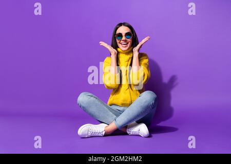 In voller Länge Foto von beeindruckt zufrieden Mädchen Arme Handflächen toothy Lächeln isoliert auf violetten Hintergrund Stockfoto