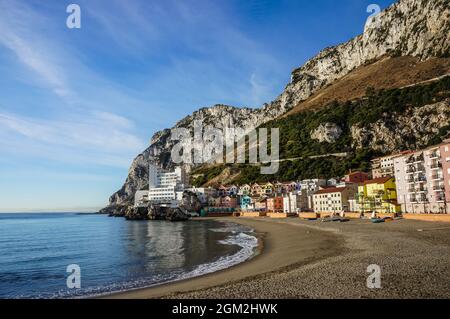 Blick am Morgen auf den Strand der katalanischen Bucht mit Caleta Hotel und anderen bunten Wohngebäuden gegen den Felsen von Gibraltar Stockfoto