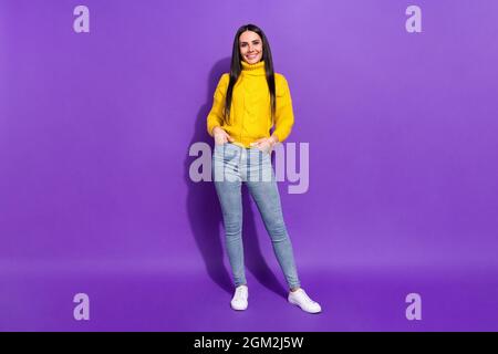 Foto in voller Größe von wunderschönen zufriedenen Mädchen stehen legte Hände in Taschen auf violettem Hintergrund isoliert Stockfoto