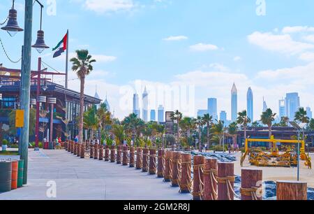 DUBAI, VAE - 4. MÄRZ 2020: Die Spaziergasse am Strand von La Mer mit Geschäften, Cafés, Palmen und der Silhouette des Burj Khalifa im Hintergrund, auf Ma Stockfoto