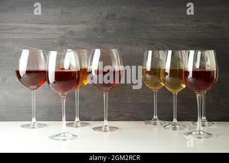 Weingläser auf weißem Tisch vor Holzhintergrund Stockfoto