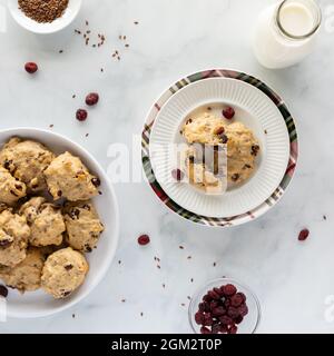 Blick von oben auf hausgemachte Cranberry-Flachs-Frühstücksplätzchen mit einer Flasche Milch, bereit zum Essen. Stockfoto