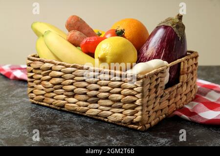 Korb mit Gemüse und Obst auf Küchentuch auf schwarzem Rauchtisch Stockfoto