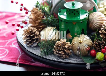 Weihnachtliche Mitteleinrichtung aus Zwiebeln, Kiefern und Beeren- und Kiefernzweigen mit einer Laterne in der Mitte. Stockfoto