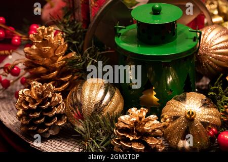 Nahaufnahme eines weihnachtlichen Mittelstücks aus Glühbirnen und Pinienkernen und einer Laterne in der Mitte. Stockfoto