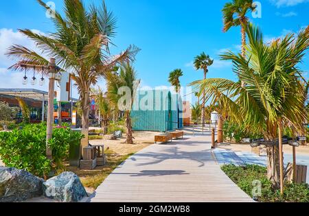 Der faule Morgenspaziergang entlang der engen grünen Gasse des öffentlichen Strandes von La Mer, Dubai, VAE Stockfoto