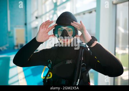 Weibliche Taucherin im Tauchanzug, die am Pool sitzt Stockfoto