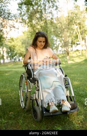 Behinderte Frau im Rollstuhl mit Mobiltelefon Stockfoto