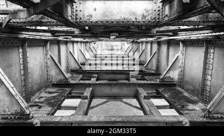 Verrostete Metallstruktur einer alten Eisenbahnbrücke, bedeckt mit Moos Stockfoto