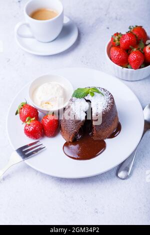 Lava Cake - Schokoladenkuchen mit Vanilleeis, Erdbeeren, Minze und Kaffee. Traditionelles französisches Gebäck. Nahaufnahme. Stockfoto