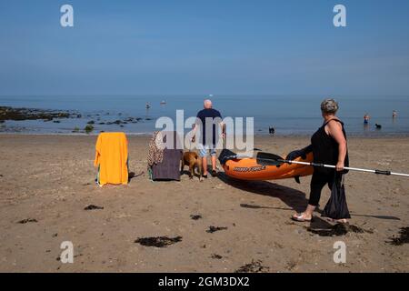 Älteres aktives Seniorenpaar am Sandstrand von New Quay in Ceredigion an der walisischen Küste mit Kajak und Liegestühlen Wales UK KATHY DEWITT Stockfoto