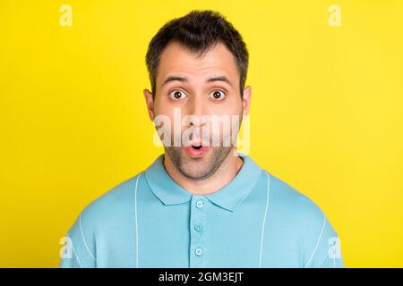 Foto von schockierten lustigen jungen Mann tragen blaue T-Shirt große Augen isoliert gelben Hintergrund Stockfoto