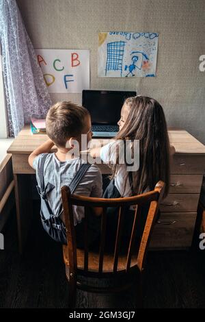 Eine Gruppe von Schulkindern oder Freunden, die Kopfhörer tragen, sitzt zu Hause in der Nähe eines Laptops. Familie, Schüler Fernunterricht, virtuelle Online-Klasse auf Laptop Stockfoto