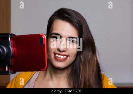 Glückliche weibliche Vlogger Live-Streaming aus dem Wohnzimmer mit Smartphone Stockfoto