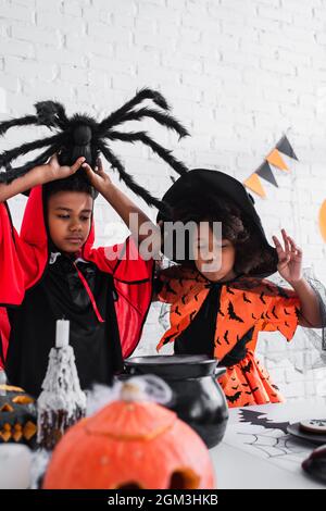 afroamerikanische Kinder in halloween Kostümen, die Trank im Hexenkessel zubereiten Stockfoto