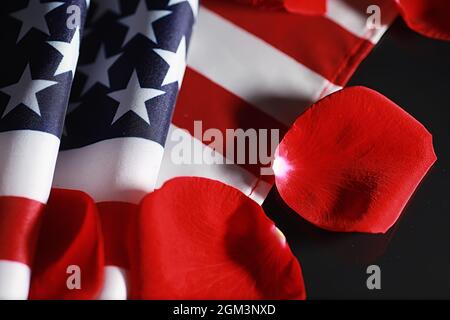 Amerikanische Flagge und Rosenblume auf dem Tisch. Symbol der Vereinigten Staaten von Amerika und rote Blütenblätter. Patriotismus und Erinnerung. Stockfoto