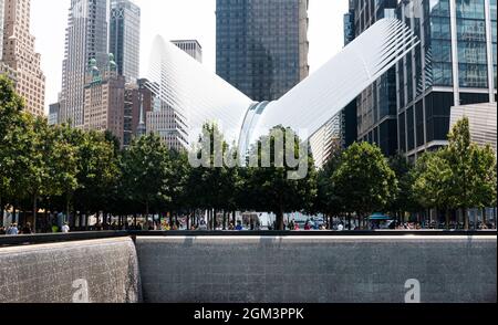 New York City, New York, USA - 28. Juli 2021: Wasser fällt in die reflektierenden Pools mit dem Gedenkmuseum für den 11. September und hohen Gebäuden im Hintergrund Stockfoto