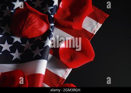 Amerikanische Flagge und Rosenblume auf dem Tisch. Symbol der Vereinigten Staaten von Amerika und rote Blütenblätter. Patriotismus und Erinnerung. Stockfoto