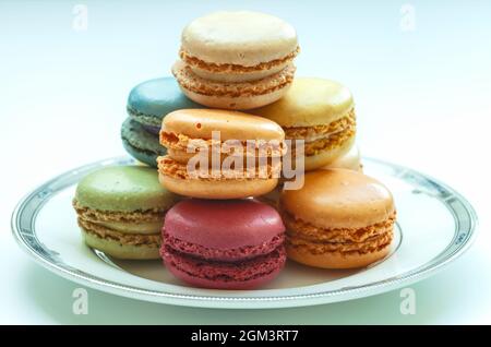 Verschiedene bunte Makronen auf Teller in weißem Hintergrund. Stockfoto