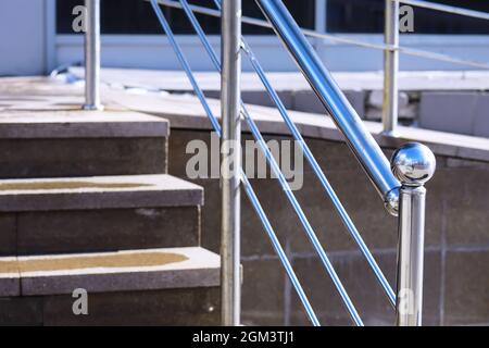 Geländer aus Glas und Edelstahl. Treppe im modernen Interieur. Glasgeländer. Niedriger Winkel Blick auf Treppen, die in Richtung eines modernen Gebäudes führen. Stockfoto