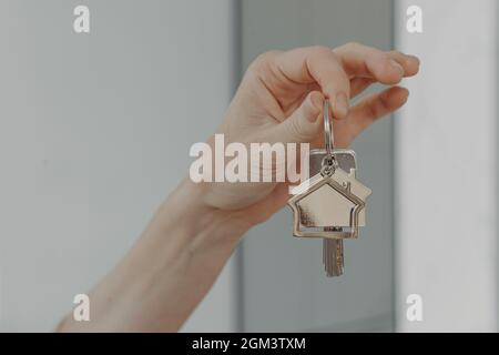 Frau, die einen hausinternen Schlüsselanhänger hält, selektive Fokussierung auf die weibliche Hand mit Schlüssel aus dem neuen Zuhause Stockfoto