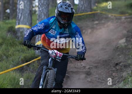 Downhillfahrer, die während eines Rennens mit Staub von hinten abfahren Stockfoto