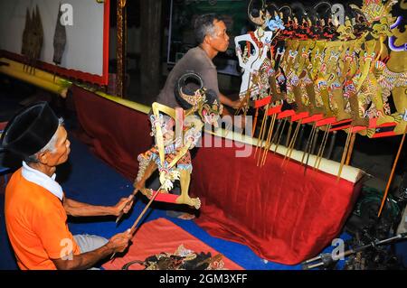 Zwei Männer arrangieren Marionetten oder Wayang kulis in Vorbereitung auf eine Schattenpuppenvorstellung. Stockfoto