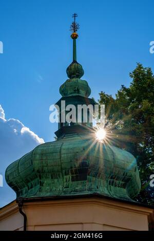 Grüner Kapellenturm mit Sonnenstrahl auf blauem Himmel Hintergrund mit Baum beleuchtet. Kloster Klokoty, Tabor, Tschechische republik. Stockfoto