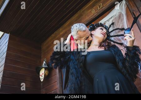 Low-Winkel-Ansicht des Mannes in halloween Vampir Kostüm beißenden Hals der Frau auf Hütte Veranda Stockfoto