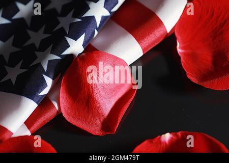 Amerikanische Flagge und Rosenblume auf dem Tisch. Symbol der Vereinigten Staaten von Amerika und rote Blütenblätter. Patriotismus und Erinnerung. Stockfoto