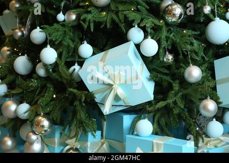 Grüner Neujahrsbaum . Das blaue Geschenk hängt von einem Tannenbaum. Konzept Hintergrund, Frohe Weihnachten, Neujahr, Winter. Geschenke und Geschenke zu Weihnachten Stockfoto