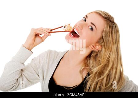 Kaukasische blonde Frau aus Polen, die Sushi auf weißem Hintergrund isst Stockfoto