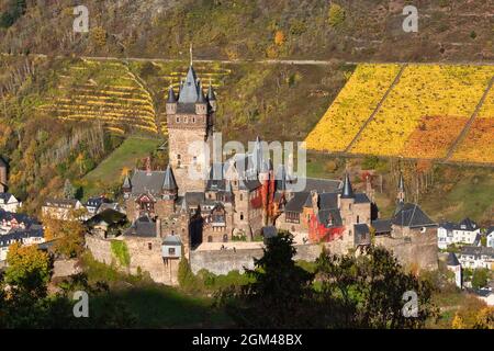 Nahaufnahme des Schlosses Reichsburg Cochem auf einem Hügel, umgeben von Weinbergen und Bäumen, an einem Herbsttag in Deutschland. Stockfoto