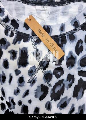 Nahaufnahme von braunem Made in China-Anhänger auf grauem und schwarzem Leopardenhemd-Muster Stockfoto
