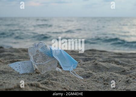 Schützende Gesichtsmaske und Plastikflasche auf marine Ökosystem, covid Verschmutzung Abfälle verworfen Stockfoto