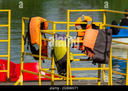 Rettungswesten hängen am gelben Zaun des Katamaranpiers. Stockfoto