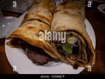 Beliebte taiwanesische Frühlingszwiebel Pfannkuchenfleisch Rolle. Taiwanesische traditionelle gebratene Pfannkuchen Crepe mit Fleisch auf dem Teller. Leckeres und leckeres chinesisches Gericht Stockfoto