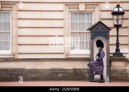 Actionfoto vom Wachwechsel am Buckingham Palace in London mit Wachen, die vom Telefonkabinenbereich marschieren. Stockfoto