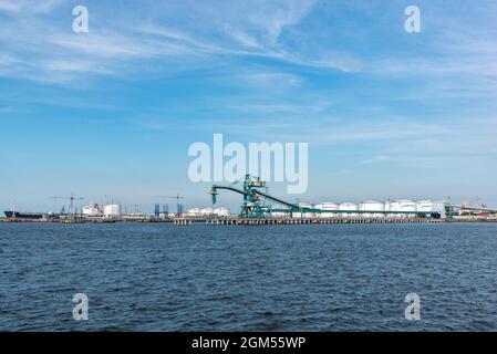 Ventspils, Lettland - 24. Juni 2021: Blick auf das Industriegebiet des Hafens von Ventspils - Terminal, Öllager, Frachtkrane. Stockfoto