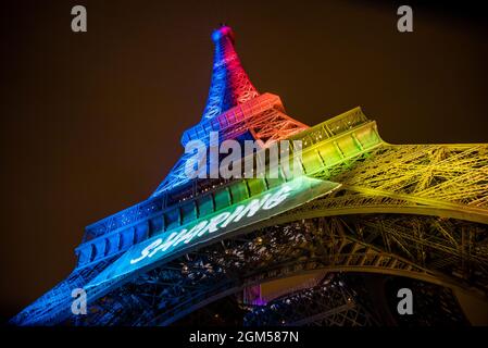 Ein weiter Blick auf den Eiffelturm, der nachts in Regenbogenfarben erstrahlt und Paris 2024 während der Vorbereitung auf die Olympischen Spiele liest. Stockfoto