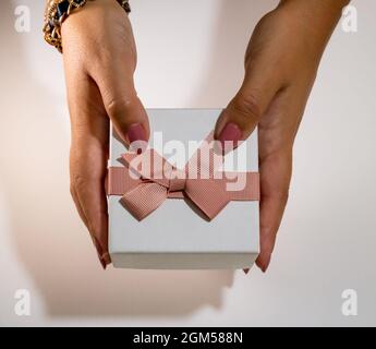 Frau Hände halten eine weiße Geschenkbox mit rosa Band Stockfoto